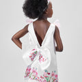 Girl in taffeta A-line dress with flamingo print, tulle sleeves, and back bow.