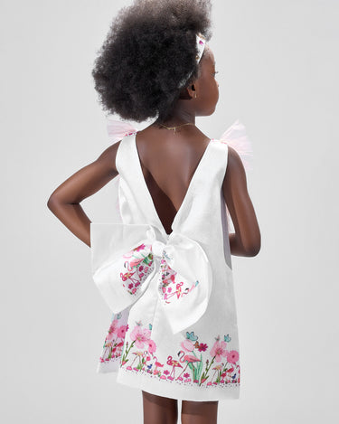 Girl in taffeta A-line dress with flamingo print, tulle sleeves, and back bow.