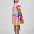 Girl in Dubai skyline print shirt dress with lace collar and puff sleeves.