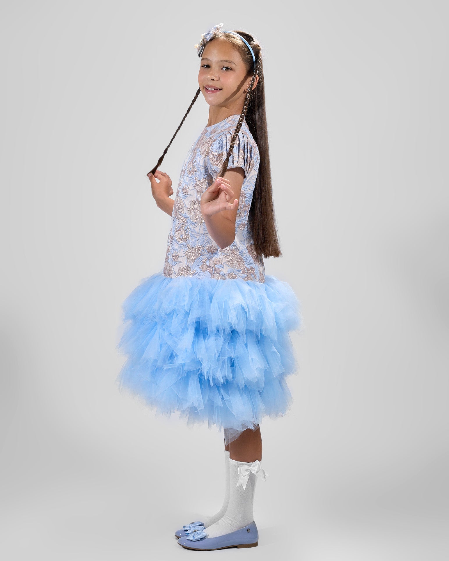 Young girl in a blue and white dress with a wand on a gray background
