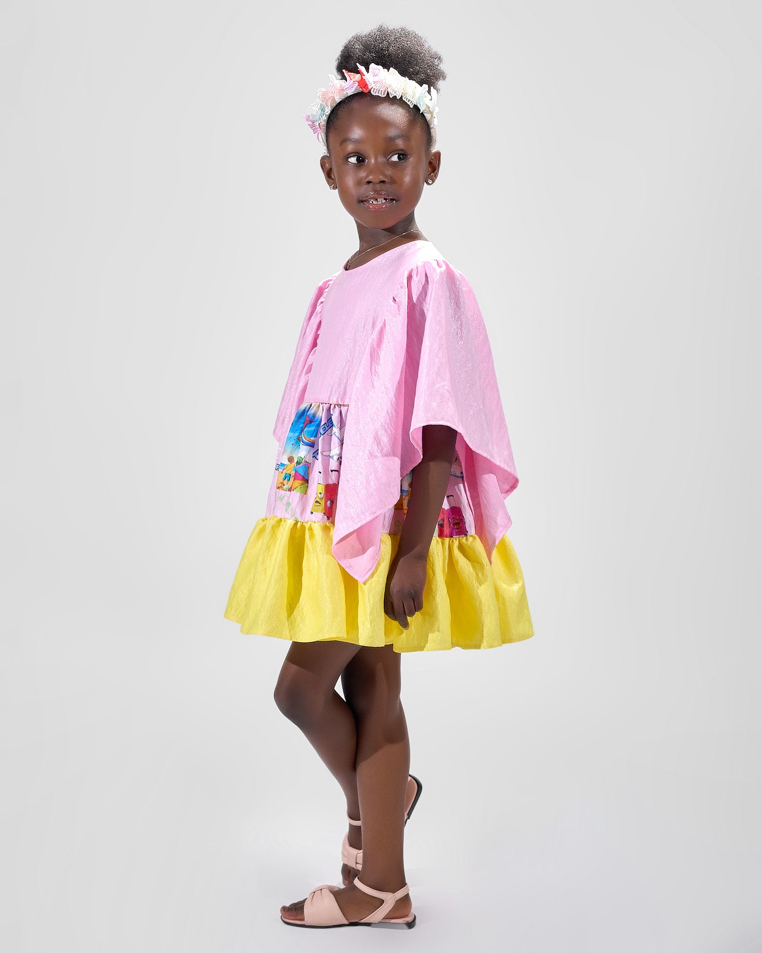 Girl in colour-block crinkle taffeta dress with yellow hem and pink sleeves.