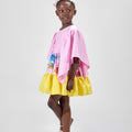 Girl in colour-block crinkle taffeta dress with yellow hem and pink sleeves.