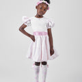 Girl in blush pink floral brocade dress with puff sleeves and organza bow.