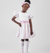Girl in blush pink floral brocade dress with puff sleeves and organza bow.