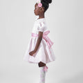 Girl in blush pink floral brocade dress with puff sleeves and organza bow.