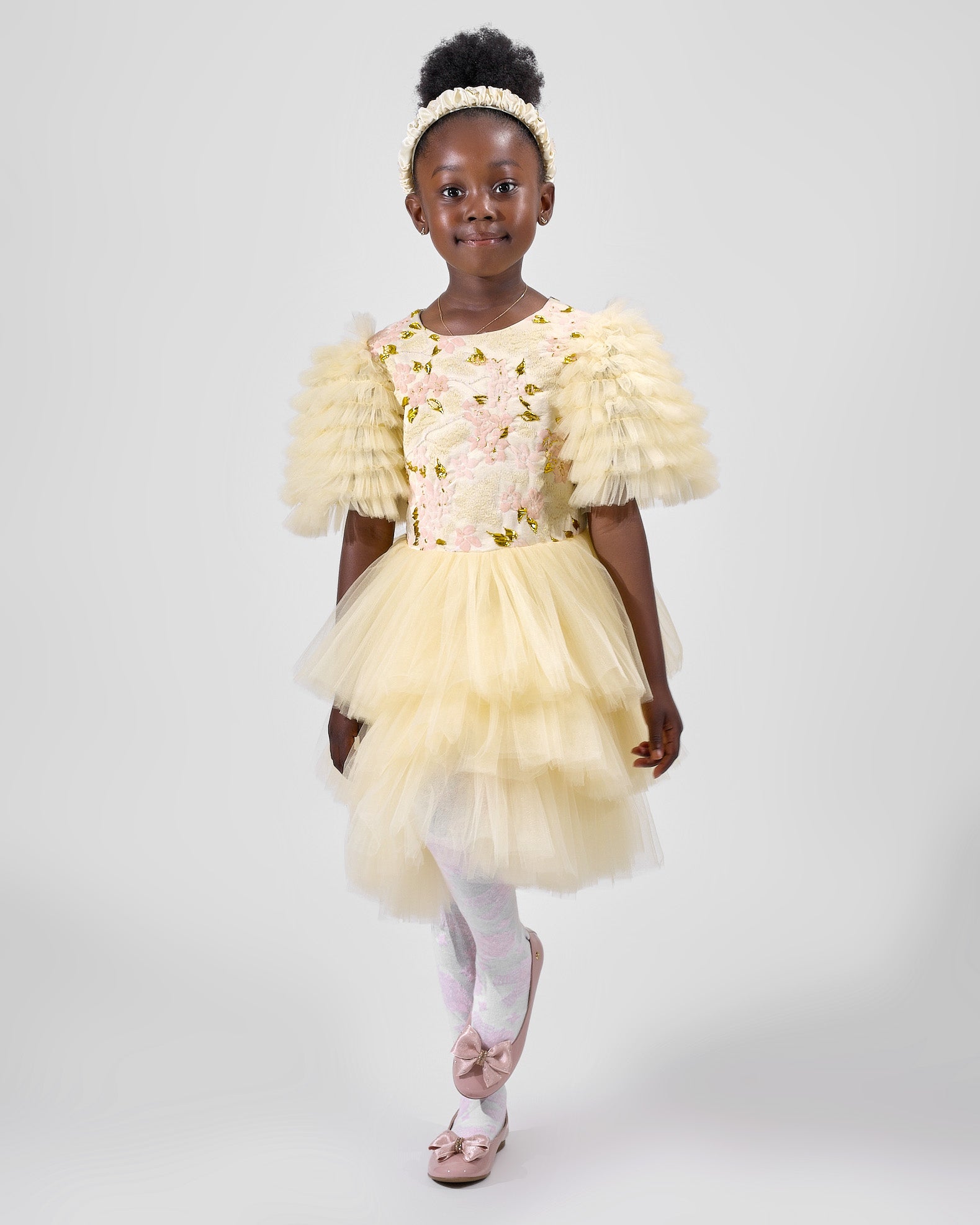 Product photo of a young girl modeling a yellow floral dress with ruffled sleeves, part of the Rehoboth Kidz summer collection, against a white background
