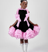 Girl in black velvet dress with pink organza ruffles and voluminous skirt.