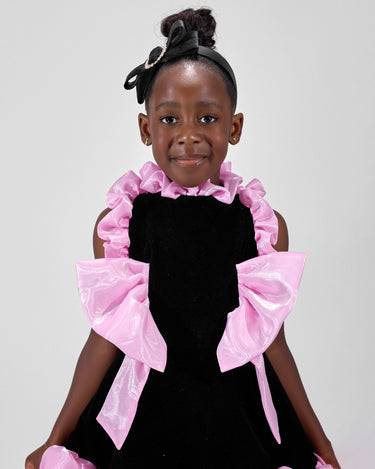 Girl in black velvet dress with pink organza ruffles and voluminous skirt.