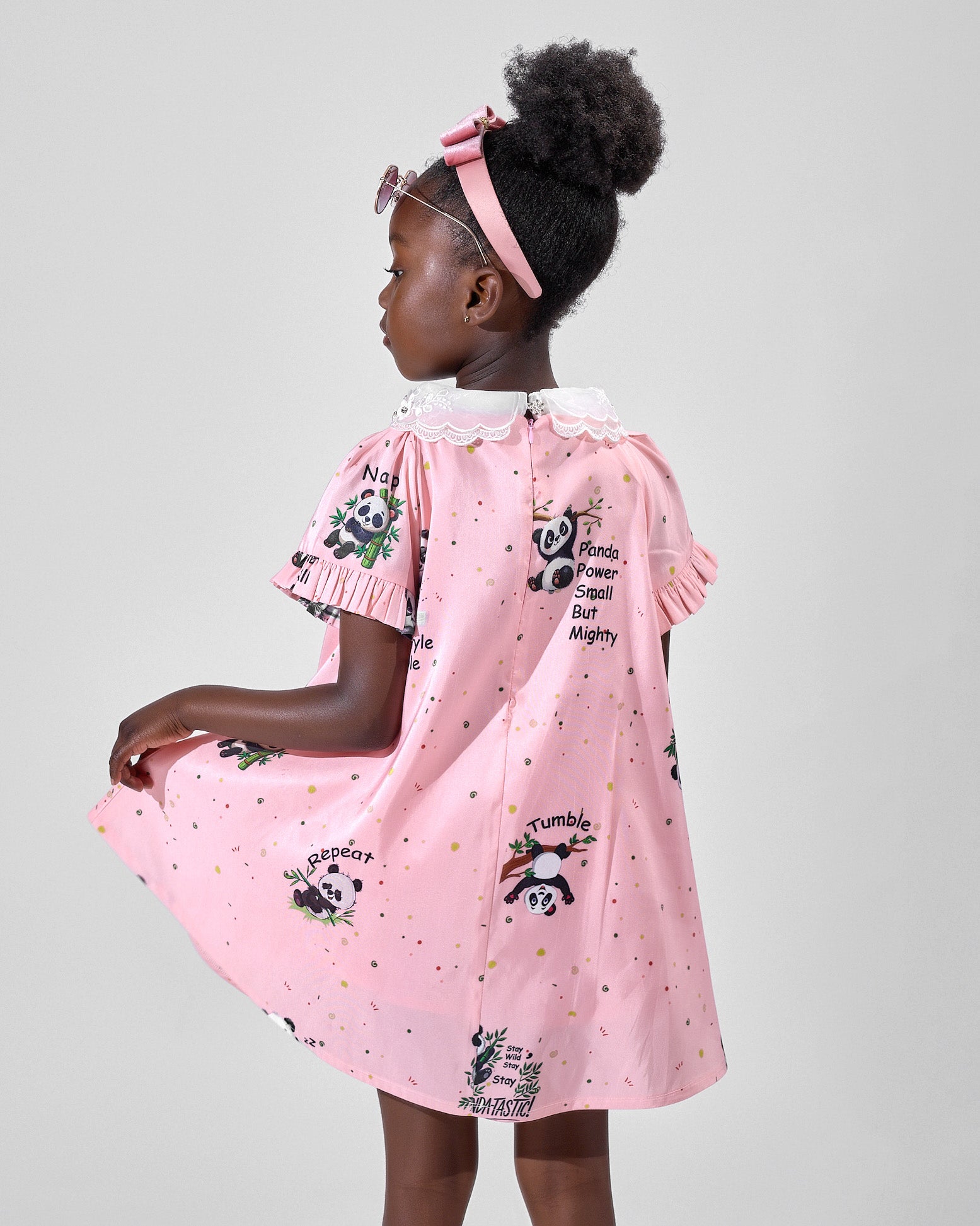 Girl in pink A-line dress with panda print and lace collar.