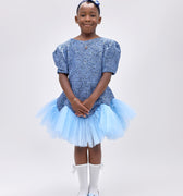 Girl wearing soft blue embroidered lace dress with puff sleeves and tulle hem.