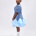 Girl wearing soft blue embroidered lace dress with puff sleeves and tulle hem.
