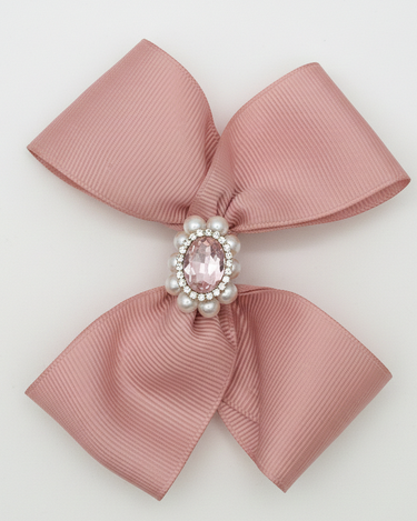 Pink bow with a central gemstone and pearls on a light gray background