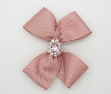 Pink bow with a central gemstone and pearls on a light gray background