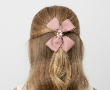 Blonde hair with a pink bow and pearl center against a white background