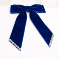 Blue velvet bow with pearl accents on a white background