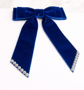 Blue velvet bow with pearl accents on a white background