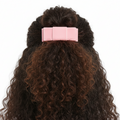 Curly hair styled with a pink barrette on a white background