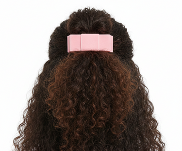Curly hair styled with a pink barrette on a white background