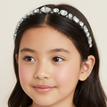 Young girl wearing a decorative headband with crystals on a plain background