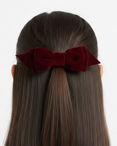 Red velvet hair bow on a person with straight hair against a white background