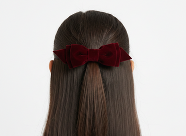 Red velvet hair bow on a person with straight hair against a white background